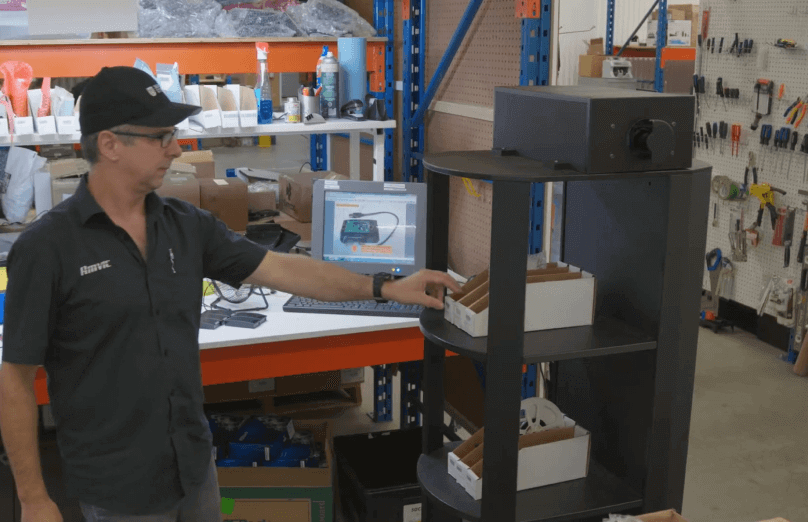 Photo d’un employé dans une usine qui va chercher une pièce dans une boîte de rangement.